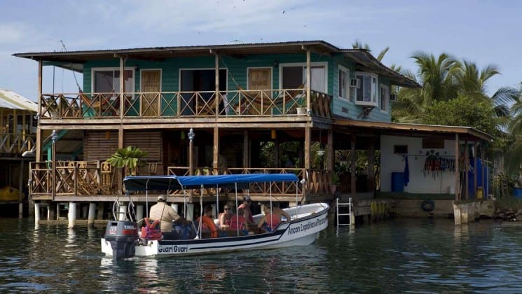 A boat full of people drives toward the Bocas Inn, situated on the water's edge, a family lodge in Bocas del Toro Panama