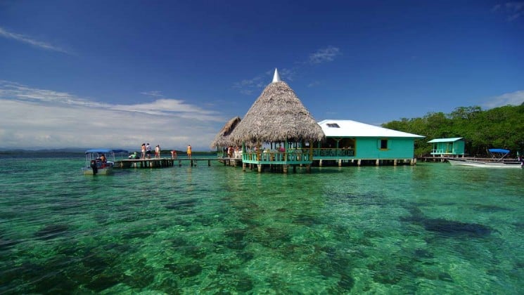 A thatch-roof hut is built on the edge of clear tropical water at Bocas Inn, in Panama