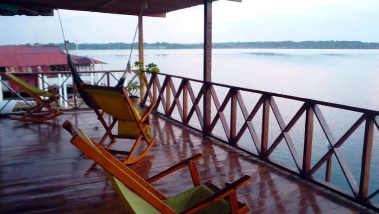 Chairs on a covered, open-air porch face the railing and the water at Bocas Inn at Bocas del Toro in Panama