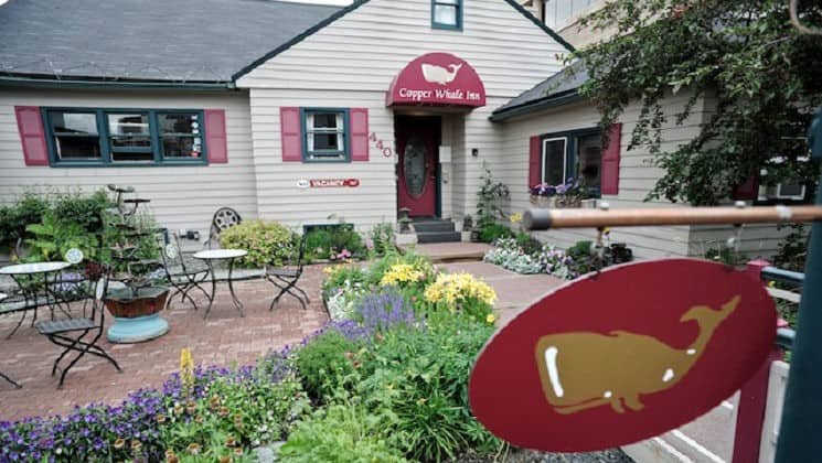 Exterior of Copper Whale Inn in Anchorage, Alaska with red sign with a painted copper whale