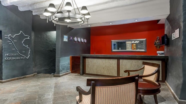 Lobby with reception desk, two seats, and large image of Peru at Costa del Sol Ramada Cusco