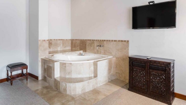 Jacuzzi with fine tiling, with TV hanging on wall nearby in suite at Costa del Sol Ramada Cusco in Peru