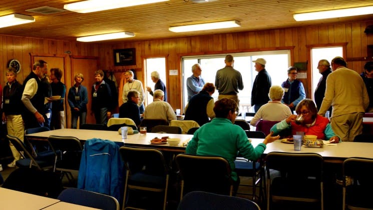 More than 20 people sit at tables or stand in line for food in the dining hall at Denali Education Center in Alaska