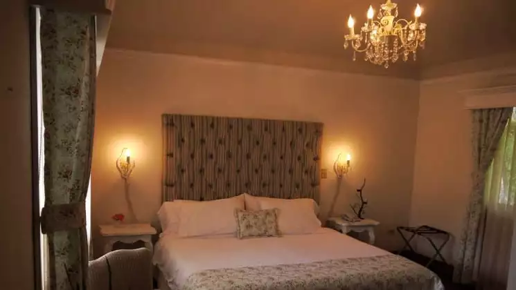 Chandelier hangs over bed in room at Finca Lerida Lodge in Panama
