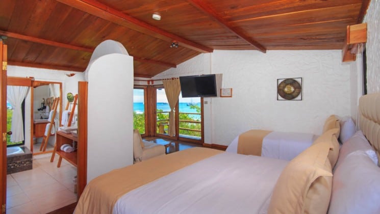 Suite with two beds, chairs, TV, tub, balcony and ocean views at Galapagos Habitat Eco Luxury Hotel on the Galapagos Island of Santa Cruz