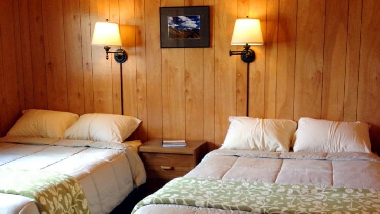 Two double beds with small table and two wall lamps at Denali Education Center near Denali National Park in Alaska