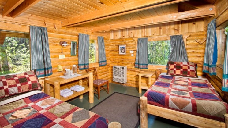 A private guest cabin at the Kenai Backcountry Lodge in Alaska features heated interiors, two beds, simple furnishings, a private porch and propane light.
