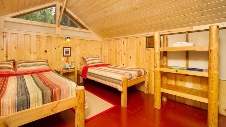 Inside a private guest cabin with two beds and simple furnishings and a propane light at the Kenai Backcountry Lodge in Alaska