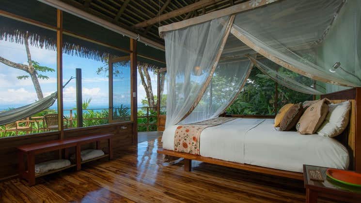 A room with a king-sized bed, balcony, hammock, and oceanview at Lapa Rios Eco Lodge, in Costa Rica's Oso Peninsula