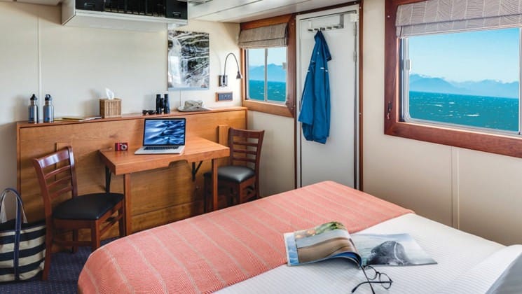 Sea Lion Category 3 stateroom with double bed, table and chairs and 2 large picture windows.