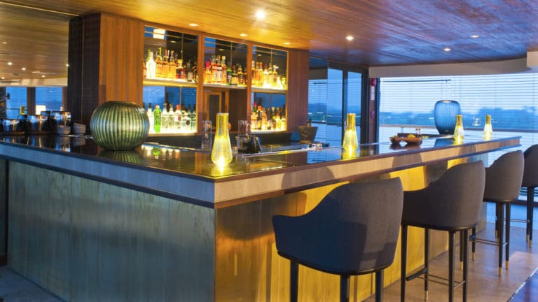 Aqua Mekong Indoor Bar with large windows, bar and tall chairs.