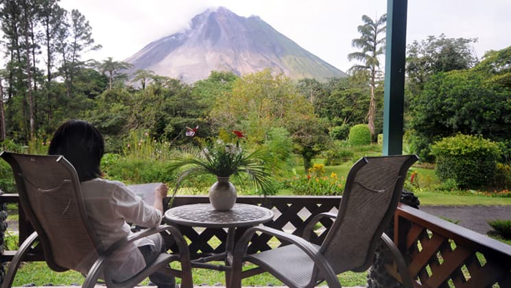 Woman sitting on private balcony of Smithsonian Room at Arenal Observatory Lodge in Costa Rica