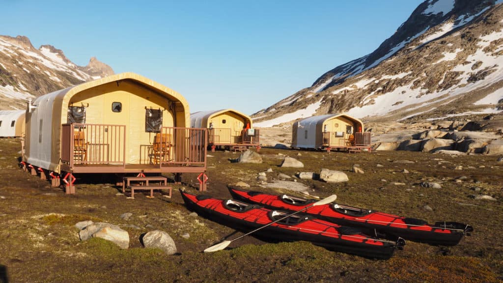 Safari-style tent cabins with two kayaks out front at Base Camp Greenland, in Sermilik Fjord