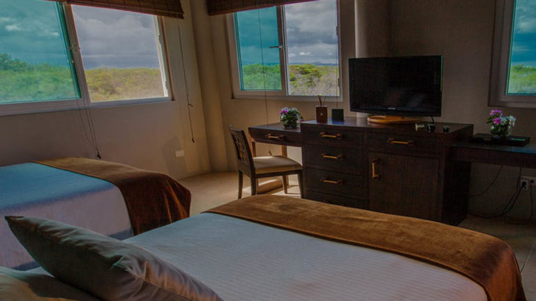 Two full beds in the Volcano View Room overlooks iconic landmarks like the scalesia forest and Sierra Negra at the Iguana Crossing Boutique Hotel, a sustainable eco resort in the Galapagos Islands