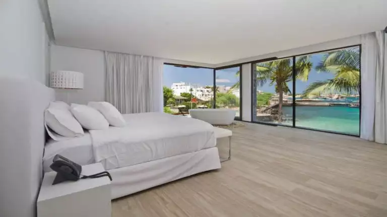 Suite interior with bed, bath, and ocean views at Golden Bay Galapagos hotel on San Cristobal in the Galapagos Islands.
