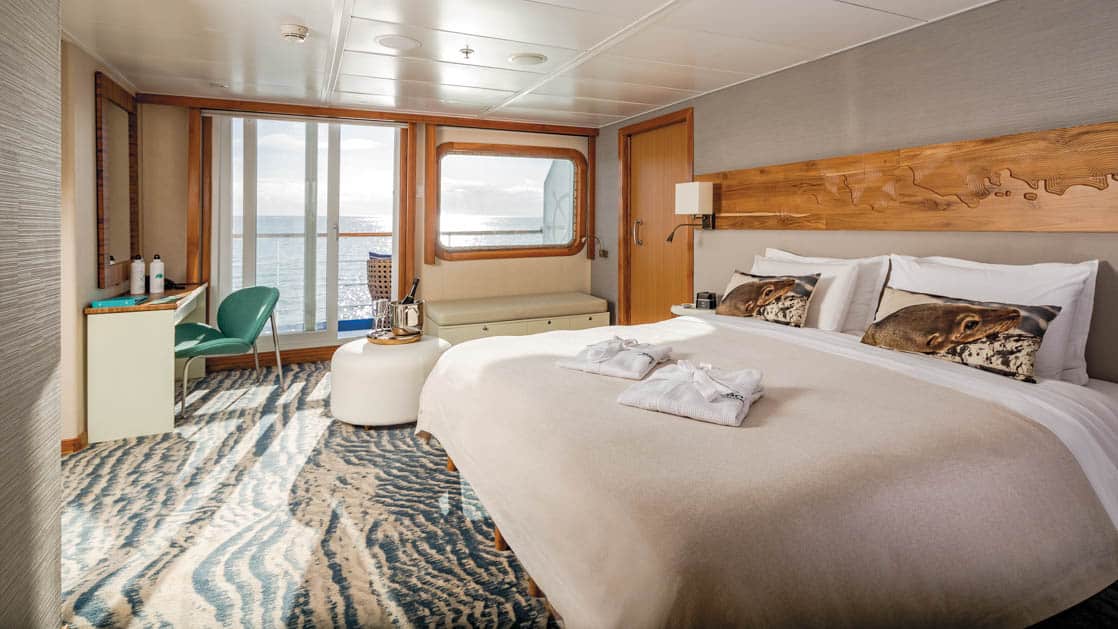 Large Balcony Suite Plus cabin on Galapagos Legend showing king bed, desk and colorful carpet