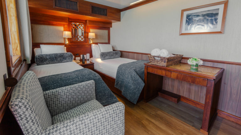 Grace suite with twin beds seating area, desk and windows.