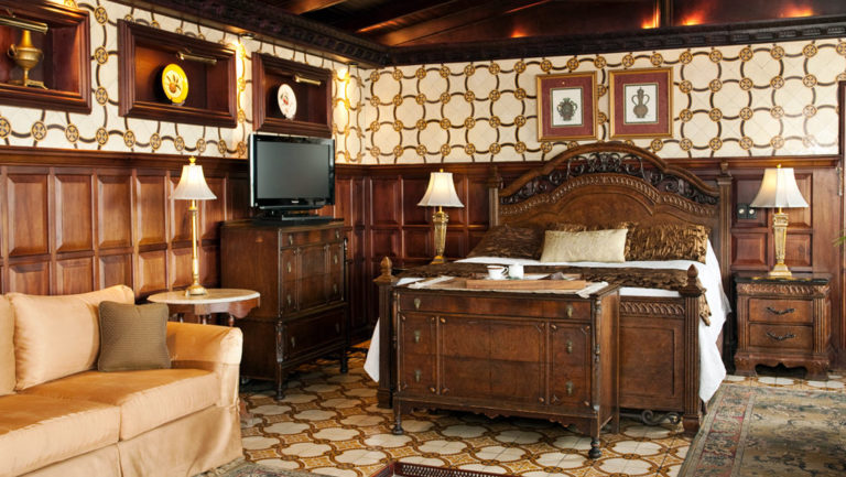 A suite at the Hotel Grano de Oro, decorated in traditional Costa Rican style and heritage, with a bed, a couch, decorative tiles and wood paneling