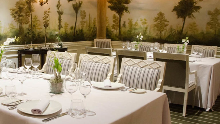 Tables are set with white tablecloths and fine dining settings at Le Gourmet, a restaurant serving upscale local and international cuisine at Hotel Oro Verde in Ecuador