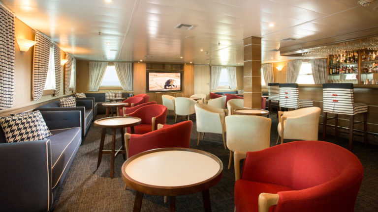 Isabella II lounge with bar, couches, chairs, tables and large viewing windows.