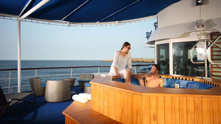 Couple relaxing and soaking in the jacuzzi on the deck of the Isabella II in the Galapagos.