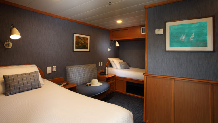 Isabela II Classic Cabin with twin beds, seating, nightstand and reading lights.