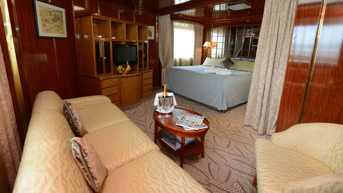Island Sky Deluxe suite with queen bed, living room with couch, chair and coffee table, sliding glass door and large window.