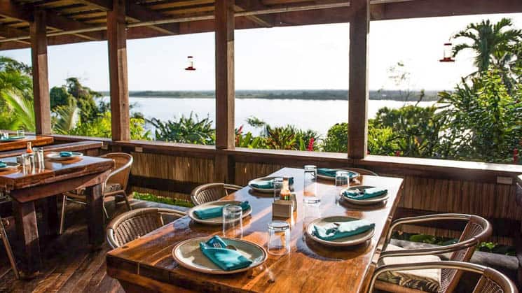 A table is set for fine dining in the open-air room overlooking the clear waters of the New River Lagoon at the Lamanai Outpost, a sustainable eco jungle lodge in Belize