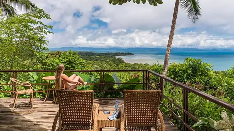Guests sitting in lounge chairs looking out over the ocean from a balcony at the Lapa Rios Eco Lodge in Costa Rica on the sun deck