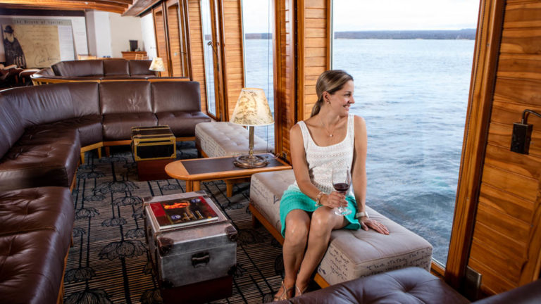 woman sitting looking out window in lounge of Galapagos Legend