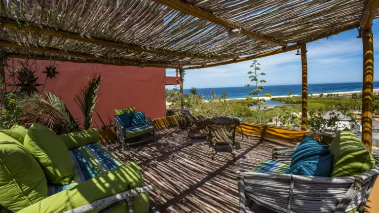 A covered patio with lounge chairs and local vegetation overlooks the desert gardens and pacific ocean at the boutique Baja hotel Los Colibris Casitas