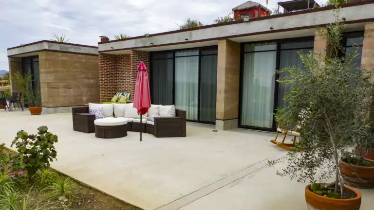 The patio outside the Babisuri house at Los Colibris Casistas, a boutique hotel in Baja, with couches, umbrella, and gardens