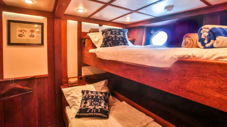 a cabin on the ombak putih small ship with stacked beds and a porthole