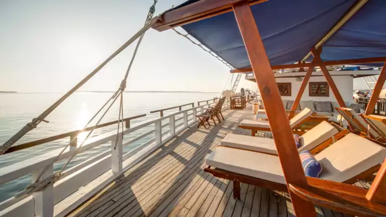 the deck of the ombak putih with a row of lounge chairs on a sunny day