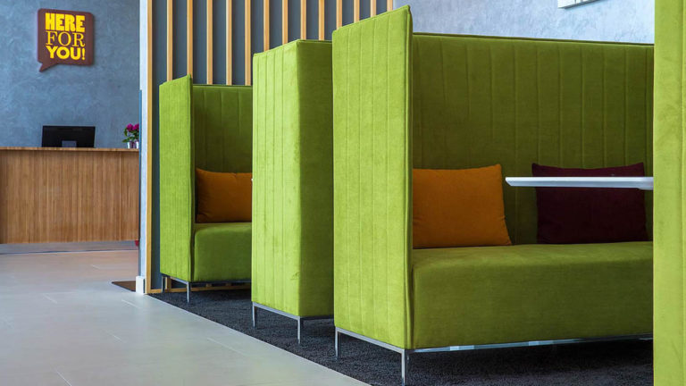 Green booths line a wall in the reception area at the Park Inn by Radisson, located in San Jose, Costa Rica