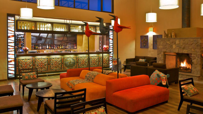 Warm lights illuminate the bar with red couches, tables and chairs, at Sol y Luna, a luxury retreat in the Andes.