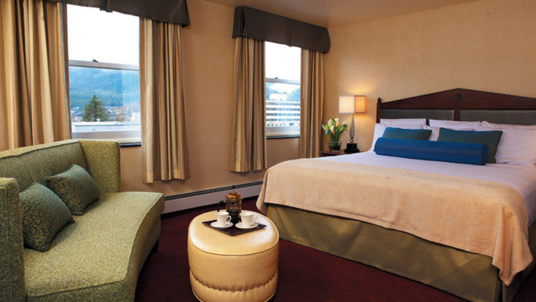 A room with a queen-sized bed and a waterfront view in the Baranof Hotel in Juneau Alaska