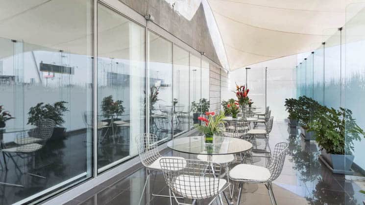 Tables and chairs are set with fresh flowers on a covered walkway at Wyndham Costa del Sol hotel, connected to the Lima International Airport
