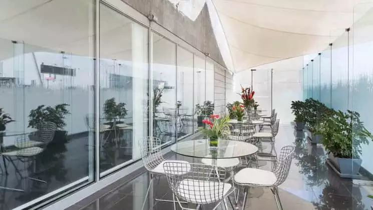 Tables and chairs are set with fresh flowers on a covered walkway at Wyndham Costa del Sol hotel, connected to the Lima International Airport