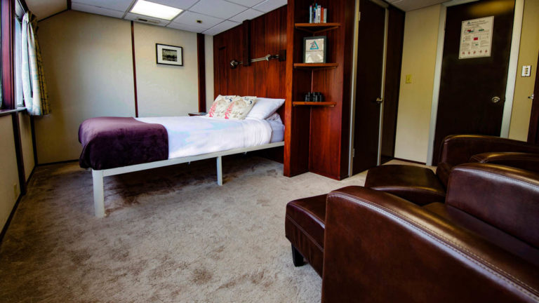 Owner's Suite aboard Alaskan Dream with big bed and two leather chairs.