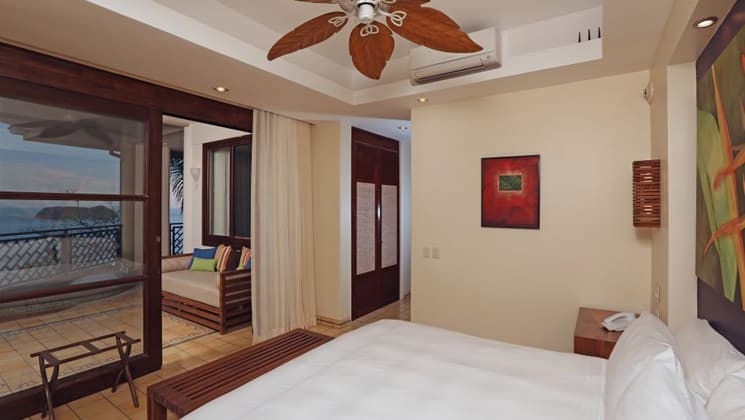 An oceanfront room with a large bed and a balcony Arenas Del Mar resort in Costa Rica.