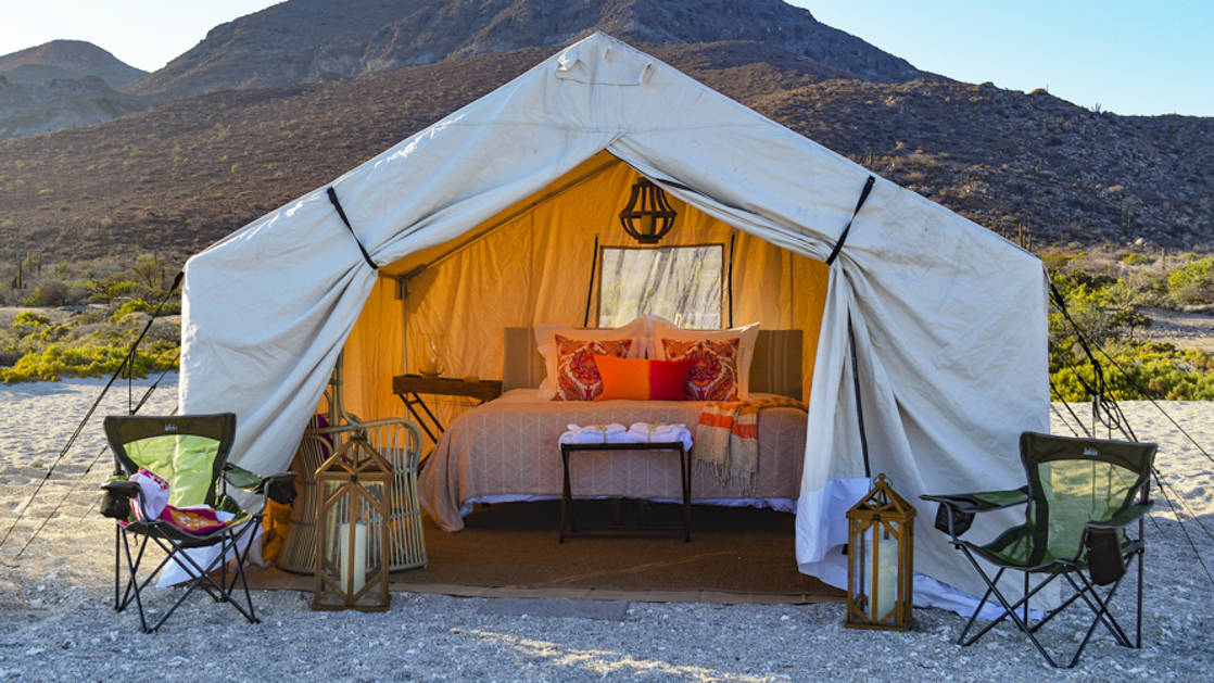 One of the luxury, beachfront, glamping tents at Camp Cecil de la Isla, located on Espiritu Santo Island in southern Baja, with a queen-sized bed, camping chairs, lanterns, and comfortable bedding.