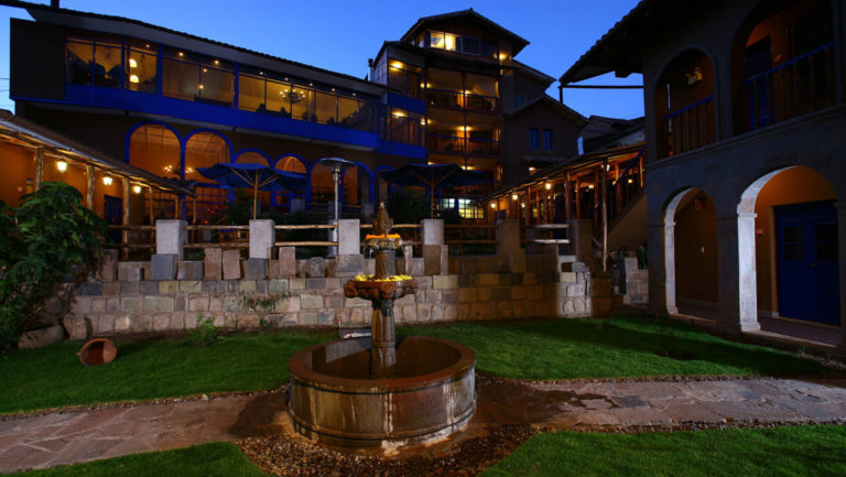 Night sets in with a view of the fountain, lawn, and courtyard at Casa Andina Premium, a hotel in Cusco, Peru.