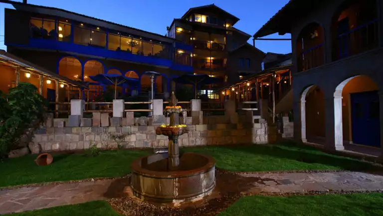 Night sets in with a view of the fountain, lawn, and courtyard at Casa Andina Premium, a hotel in Cusco, Peru.