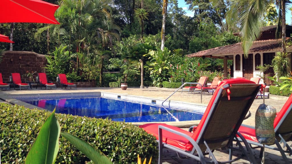 Large pool with lounge chairs and shady umbrellas at Casa Corcovado Jungle Lodge in Costa Rica
