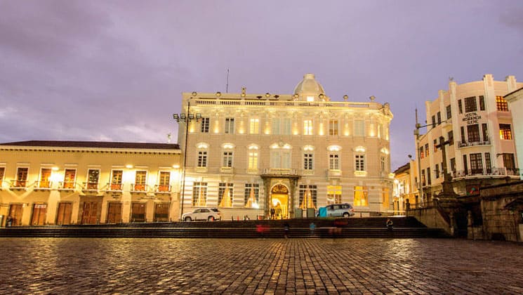 Cobblestone street plaza in front of bright, well-lit Casa Gangotena hotel and historic mansion in Quito, Ecuador