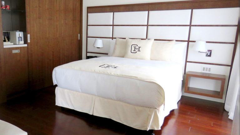 Large bed with wood detailing and kitchenette in the Presidential Suite at Central Hotel Panama in Panama City