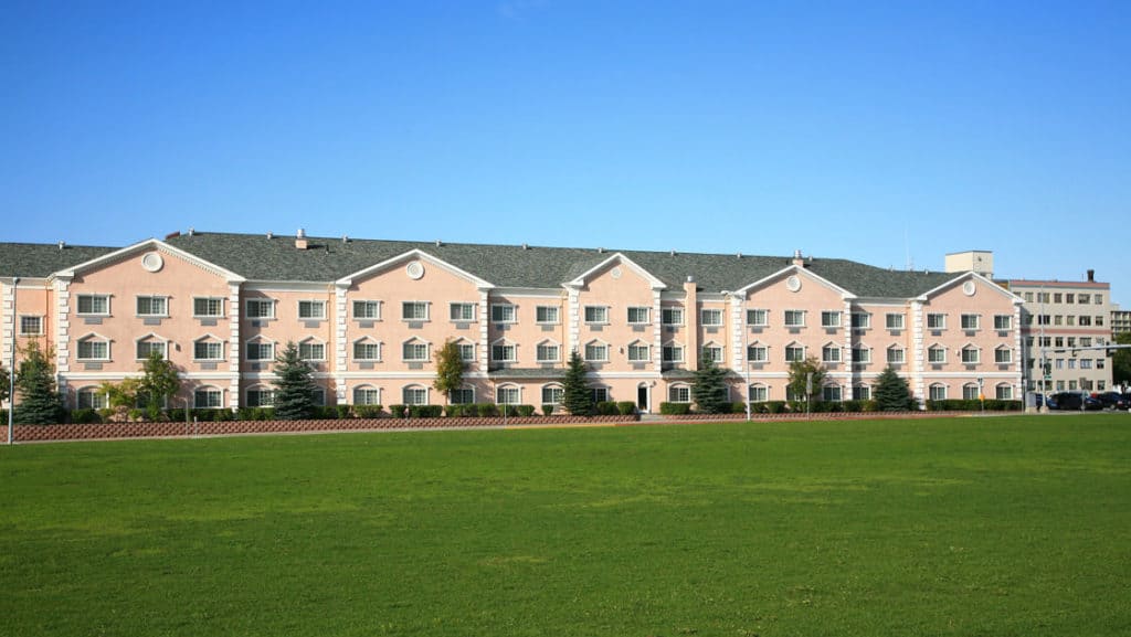 Exterior of Clarion Suites, with large green lawn and blue skies in Anchorage