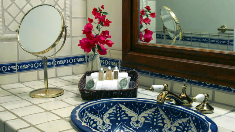 The bathroom of the garden suite, with a blue tiled sink and white tiled vanity, fresh flowers, at Todos Santos Inn, an old hacienda hotel in Baja