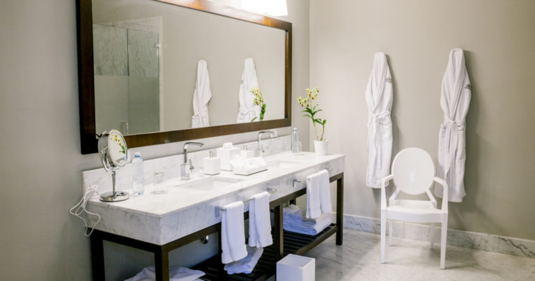 Large mirror, twin sinks and chair in bathroom of Park Suite at Hotel del Parque in Guayaquil, Ecuador